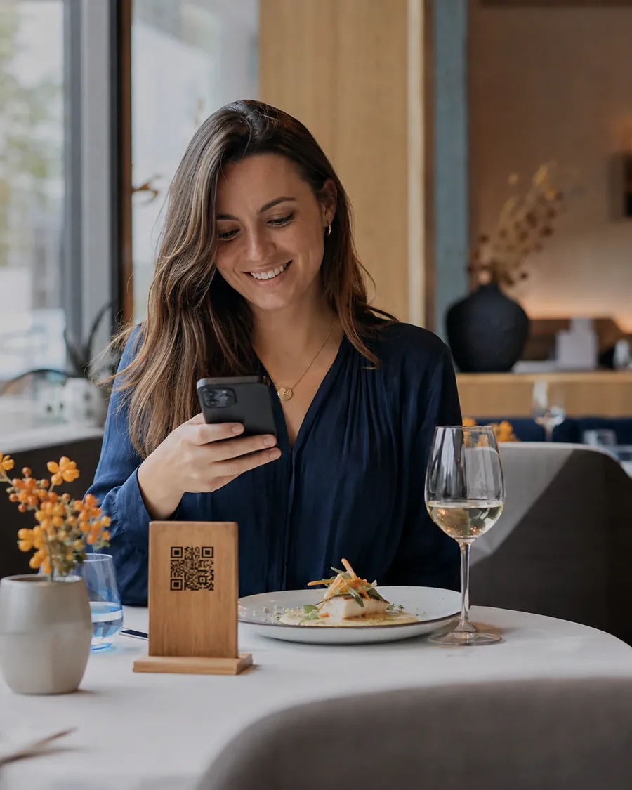 Gästin scannt den QR-Code am gedeckten Tisch und bestellt per Smartphone